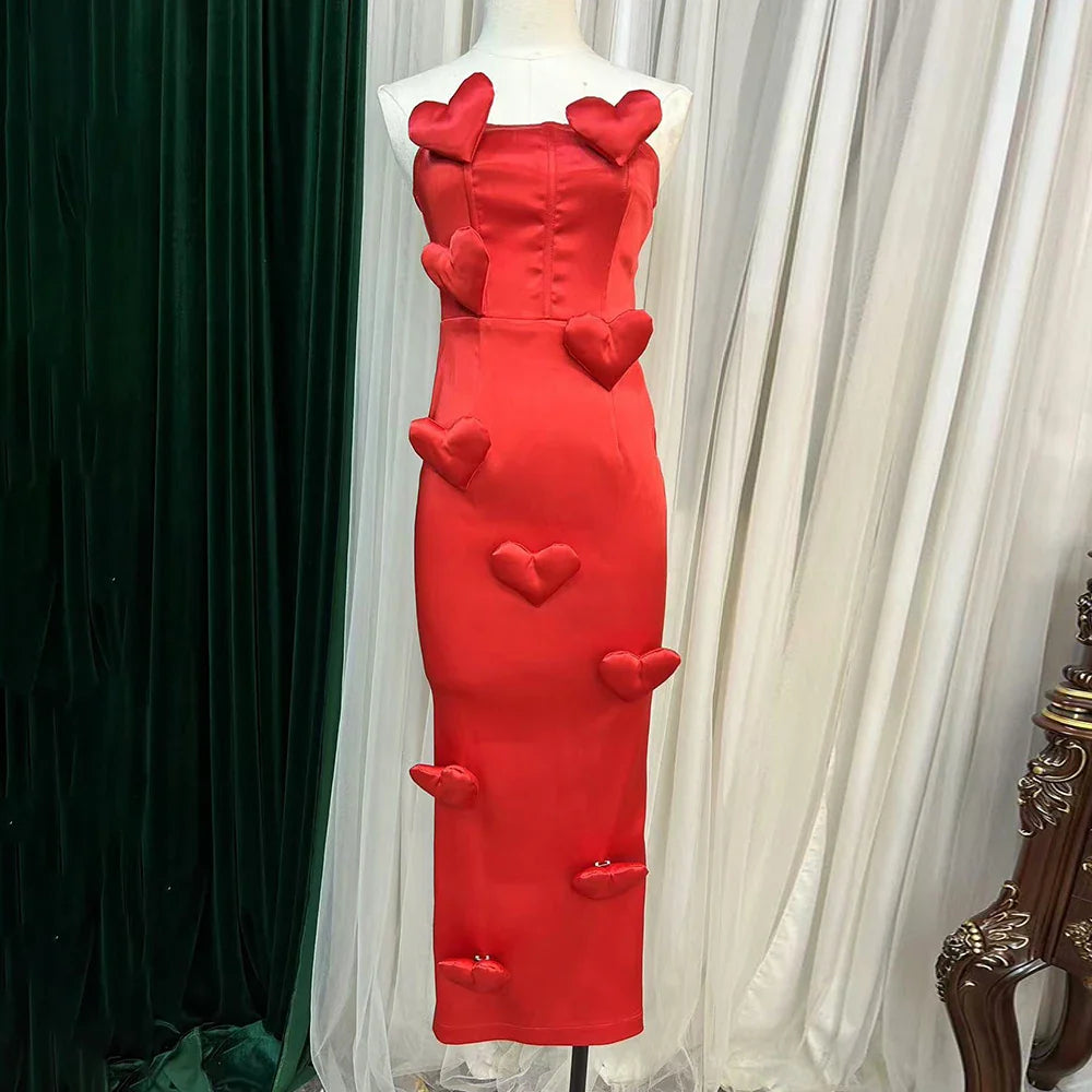 Red dress with heart designs on a mannequin against a white curtain background