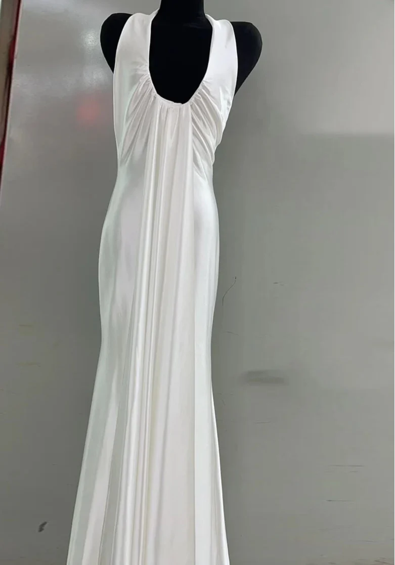 White evening gown on a mannequin against a plain background