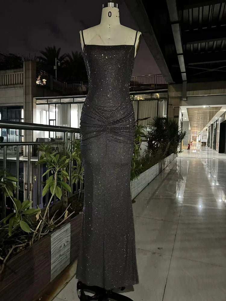 Black sequin evening gown on a mannequin in an outdoor setting with plants and building in the background.