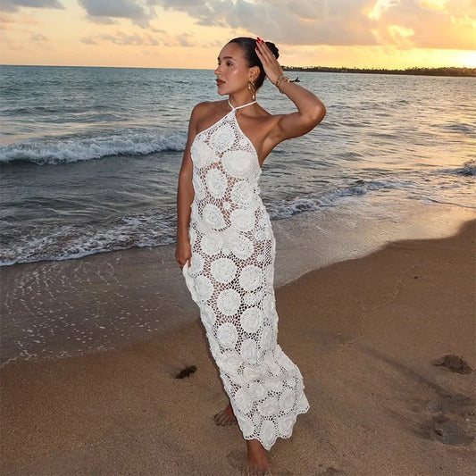 Woman in a white lace dress standing on a beach at sunset