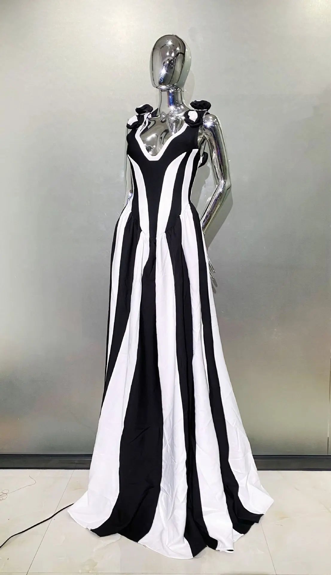Mannequin wearing a black and white striped evening gown against a neutral background