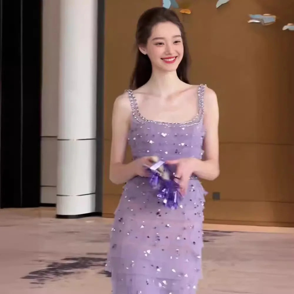 Woman in a purple sequined dress holding a purple object indoors.