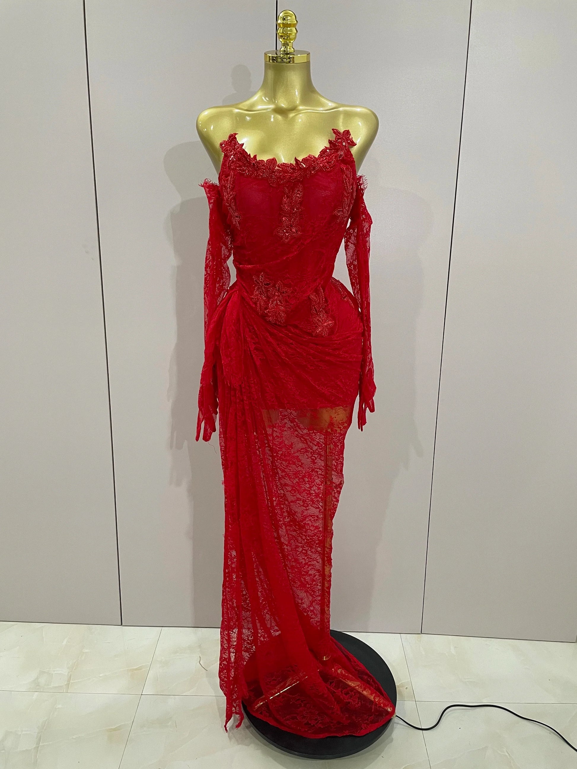 Red lace dress on a mannequin against a plain background