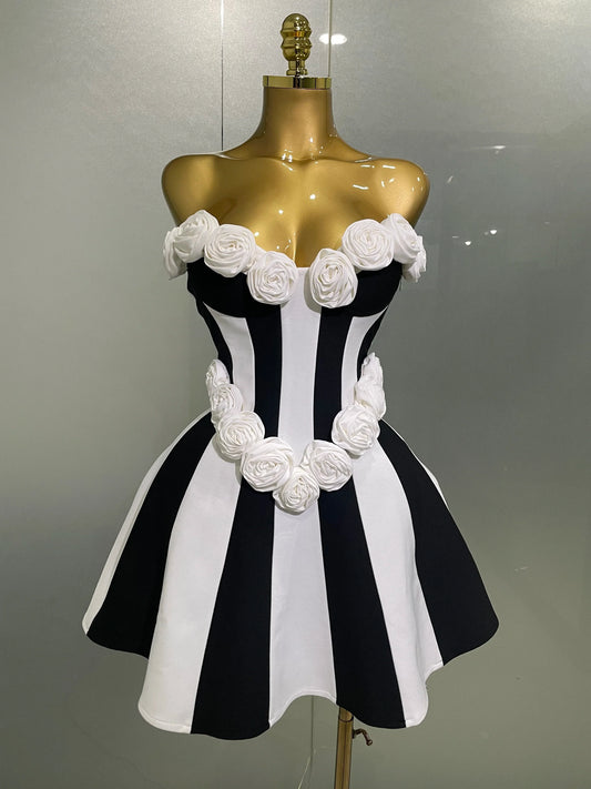 Black and white striped dress with floral details on a mannequin against a gray background