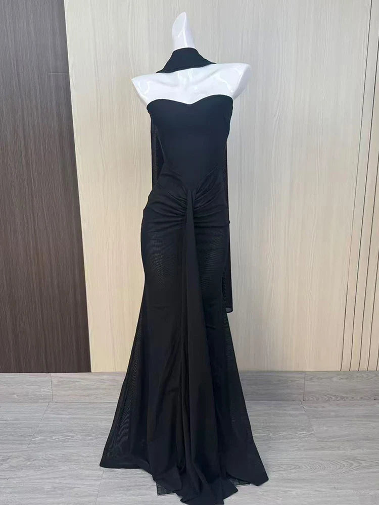 Black evening gown with white neckline on a mannequin against a wooden panel background