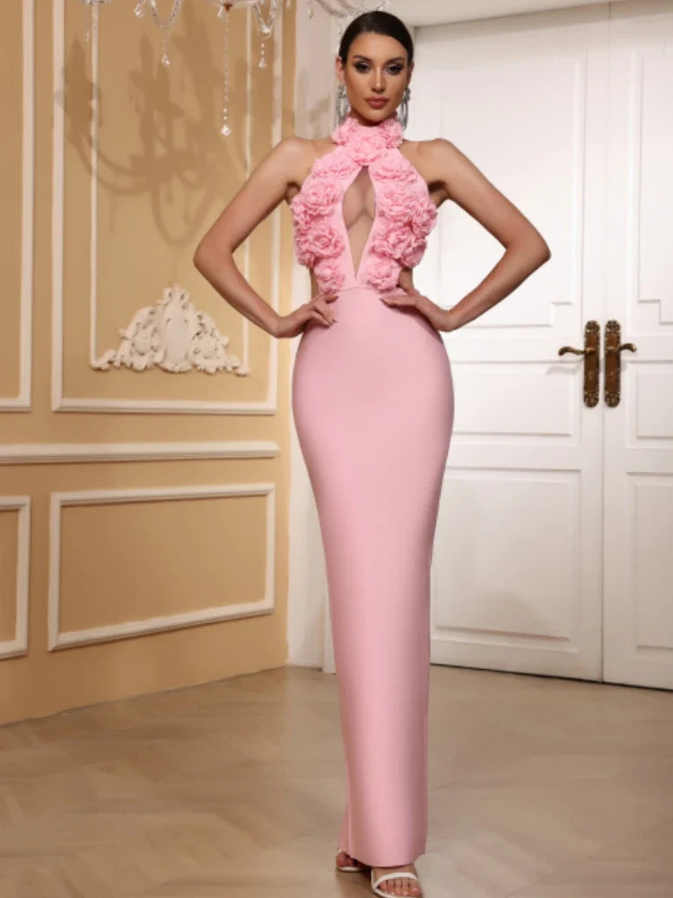 Woman wearing a pink evening gown with floral details in an elegant room.