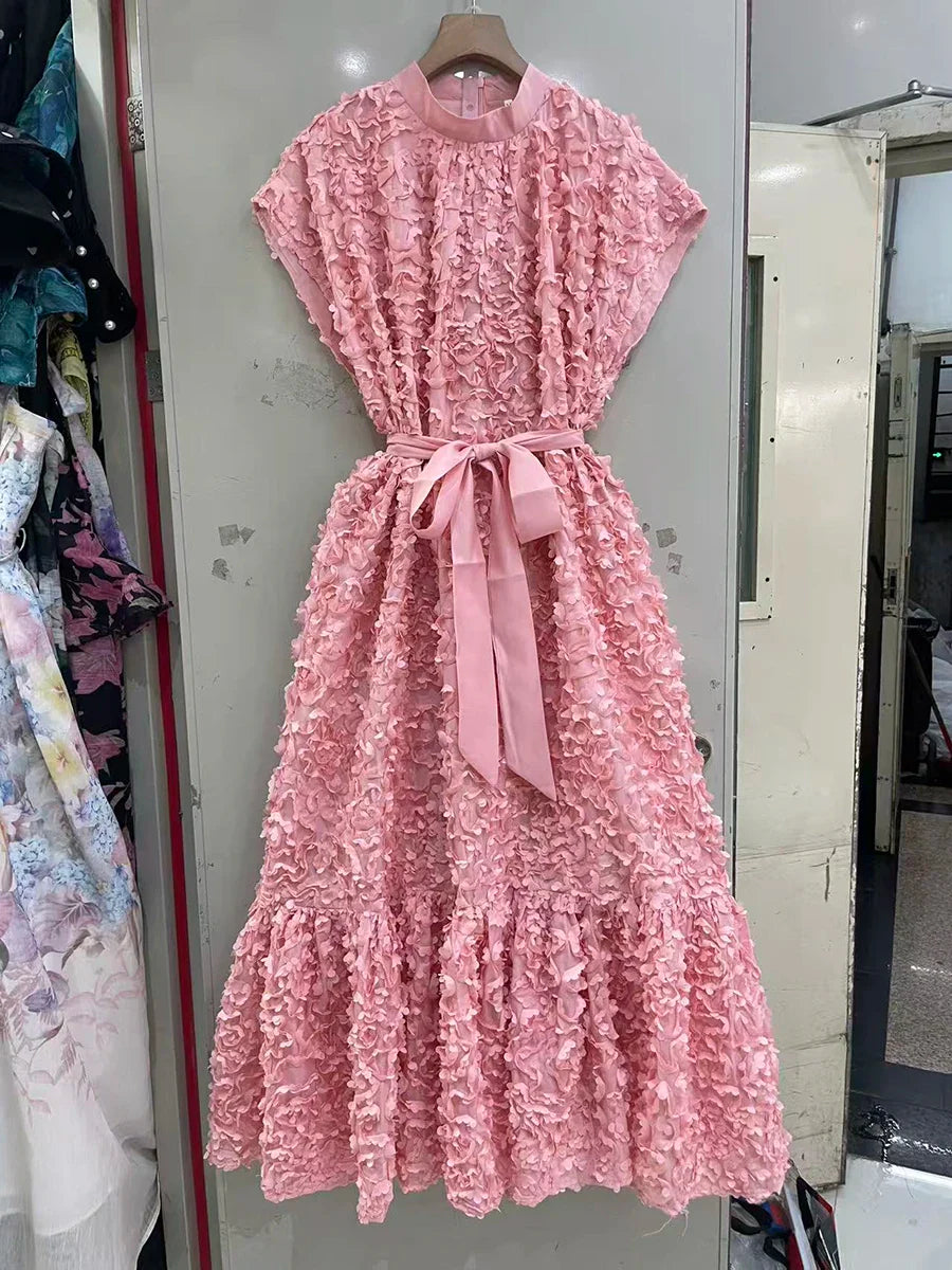 Pink lace dress with a bow tie on a hanger against a neutral background