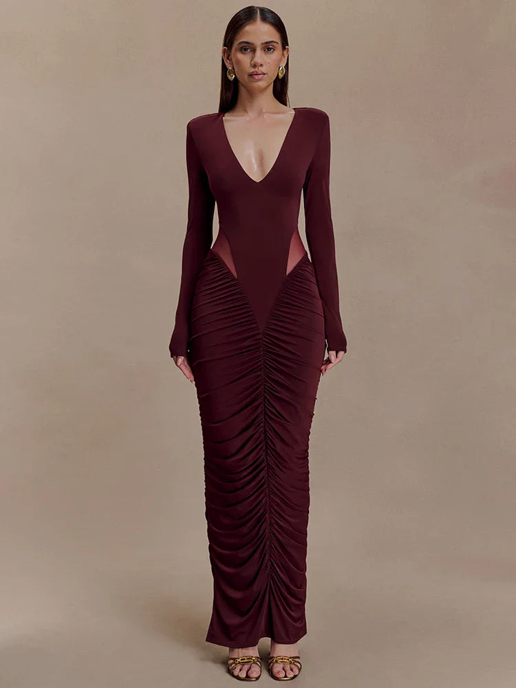 Woman wearing a burgundy evening gown with a deep neckline and ruched design on a beige background