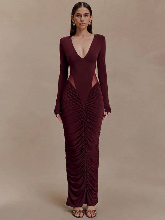 Woman wearing a burgundy evening gown with a deep neckline and ruched design on a beige background