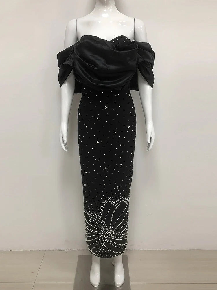 Black evening gown with floral embellishments on a mannequin against a white background
