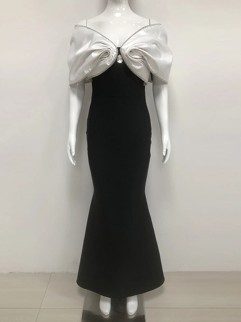 Mannequin wearing a black dress with a silver bow detail on a white background