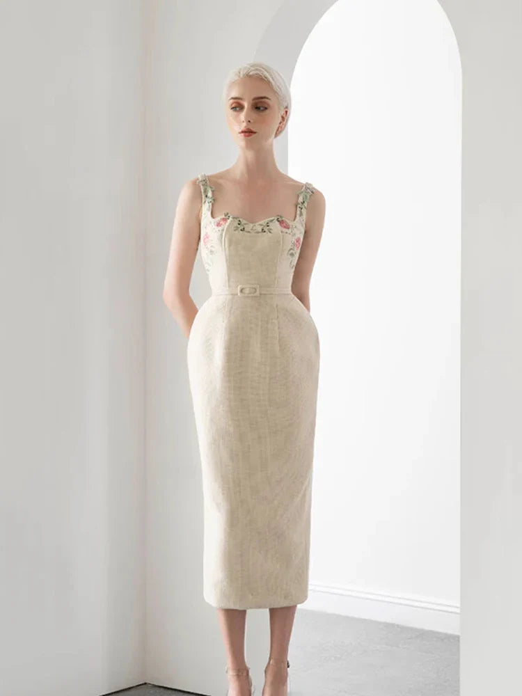 Woman wearing a beige dress with floral details in a minimalistic setting