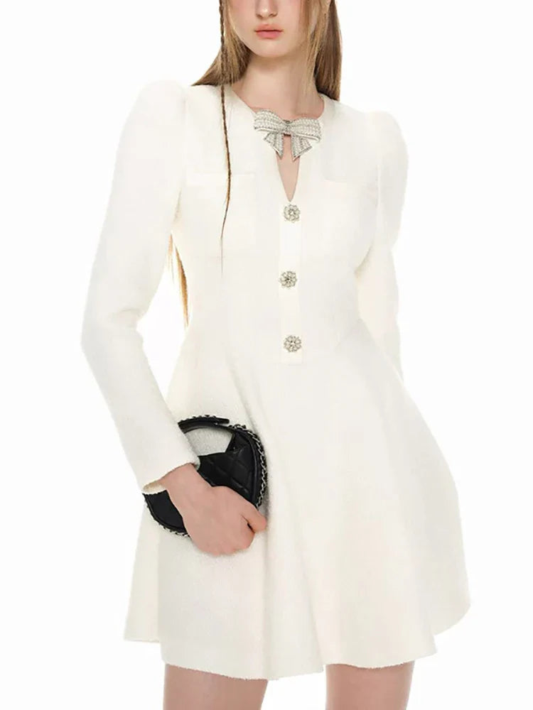 White dress with buttons and a black clutch held by a person