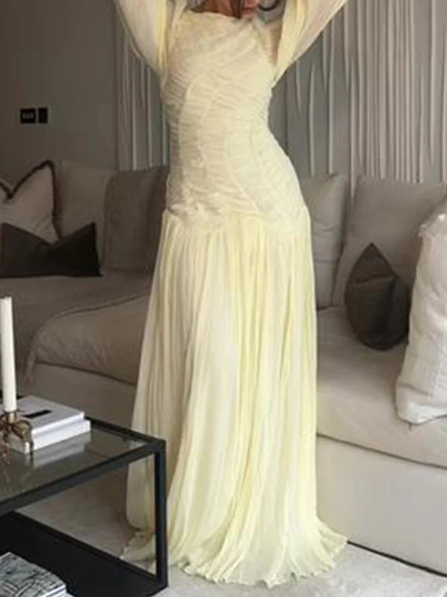 Woman in a long, light-colored dress standing in a living room.