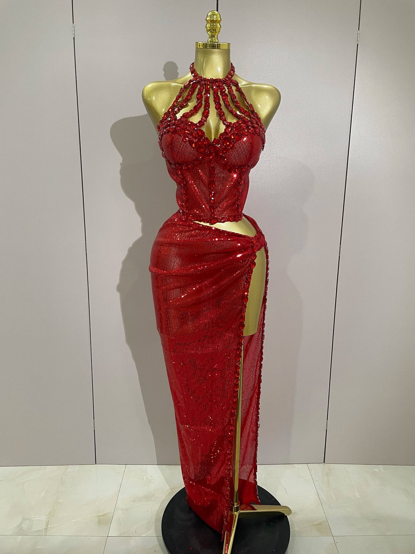 Red beaded evening gown on a mannequin against a plain background