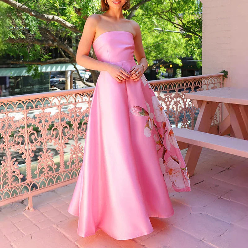 Woman in a pink strapless dress holding a floral clutch on a balcony.