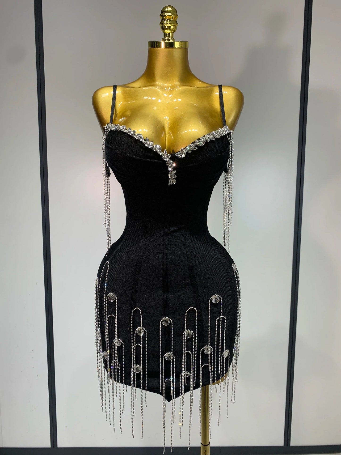 Black dress with silver embellishments on a mannequin against a neutral background
