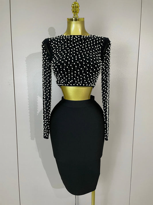 Black dress set with pearl embellishments on a mannequin against a white background