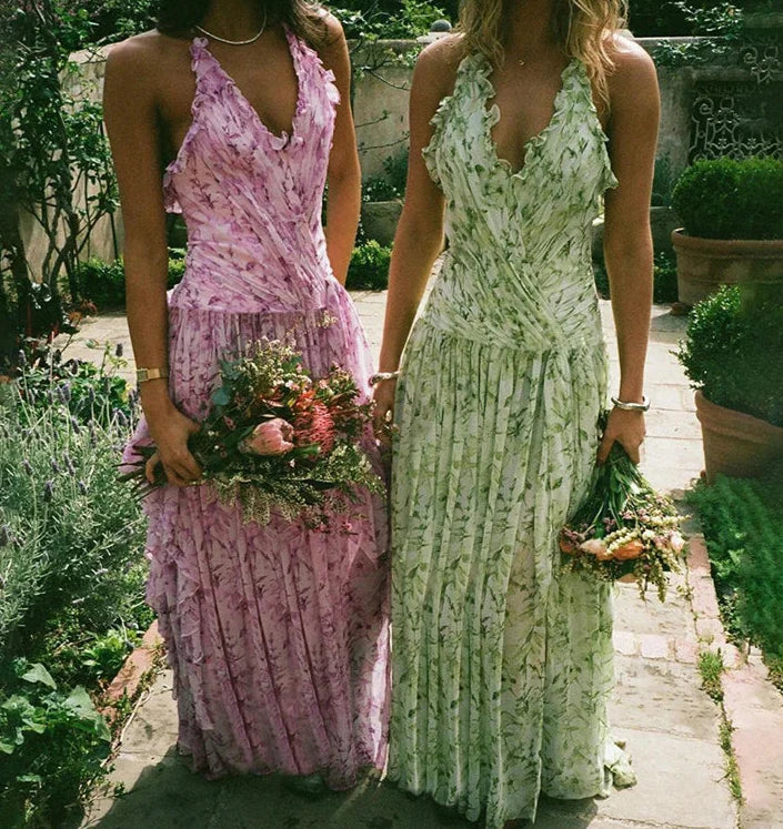 Two women in floral dresses standing outdoors with flowers.