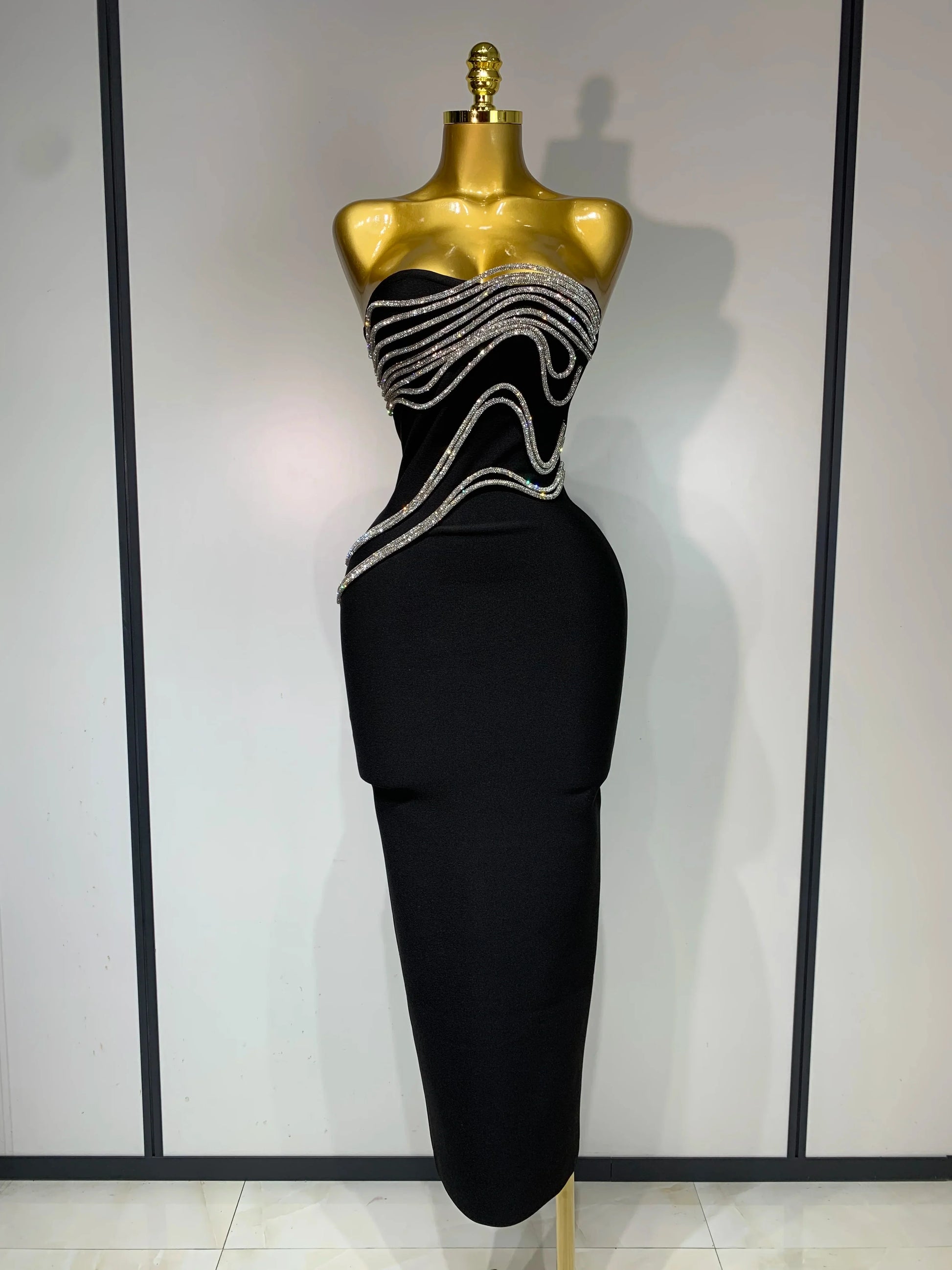 Black evening gown with silver embellishments on a mannequin against a neutral background