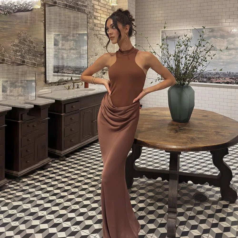 Woman in a brown dress standing in a stylishly decorated room with a table and decorative elements.