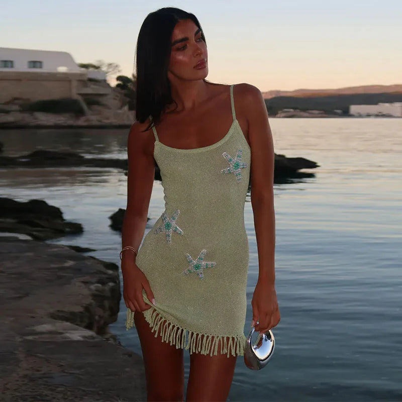 Woman in a light green dress with starfish patterns standing by a body of water.