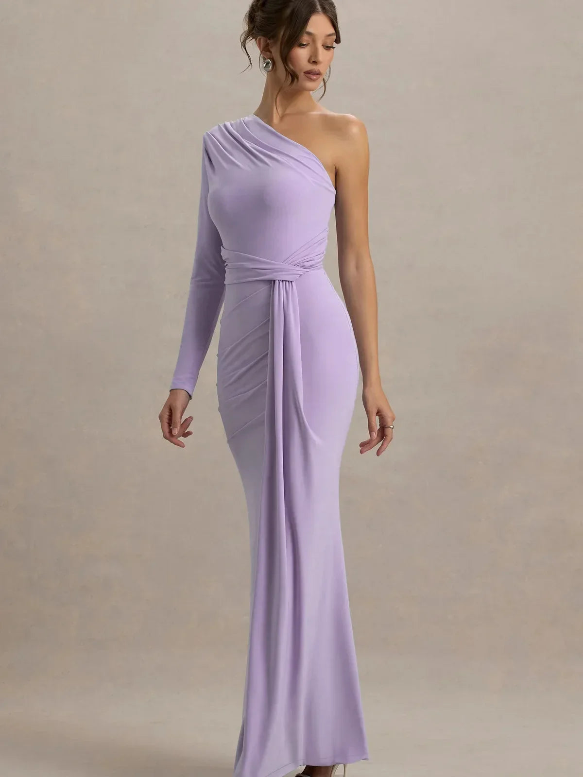Woman wearing a one-shoulder lavender dress against a plain background