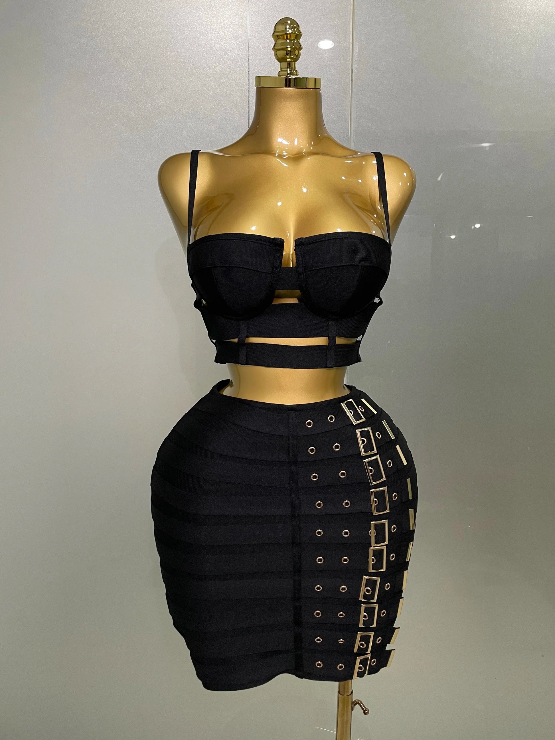Black dress with cut-out design on a gold mannequin against a white background