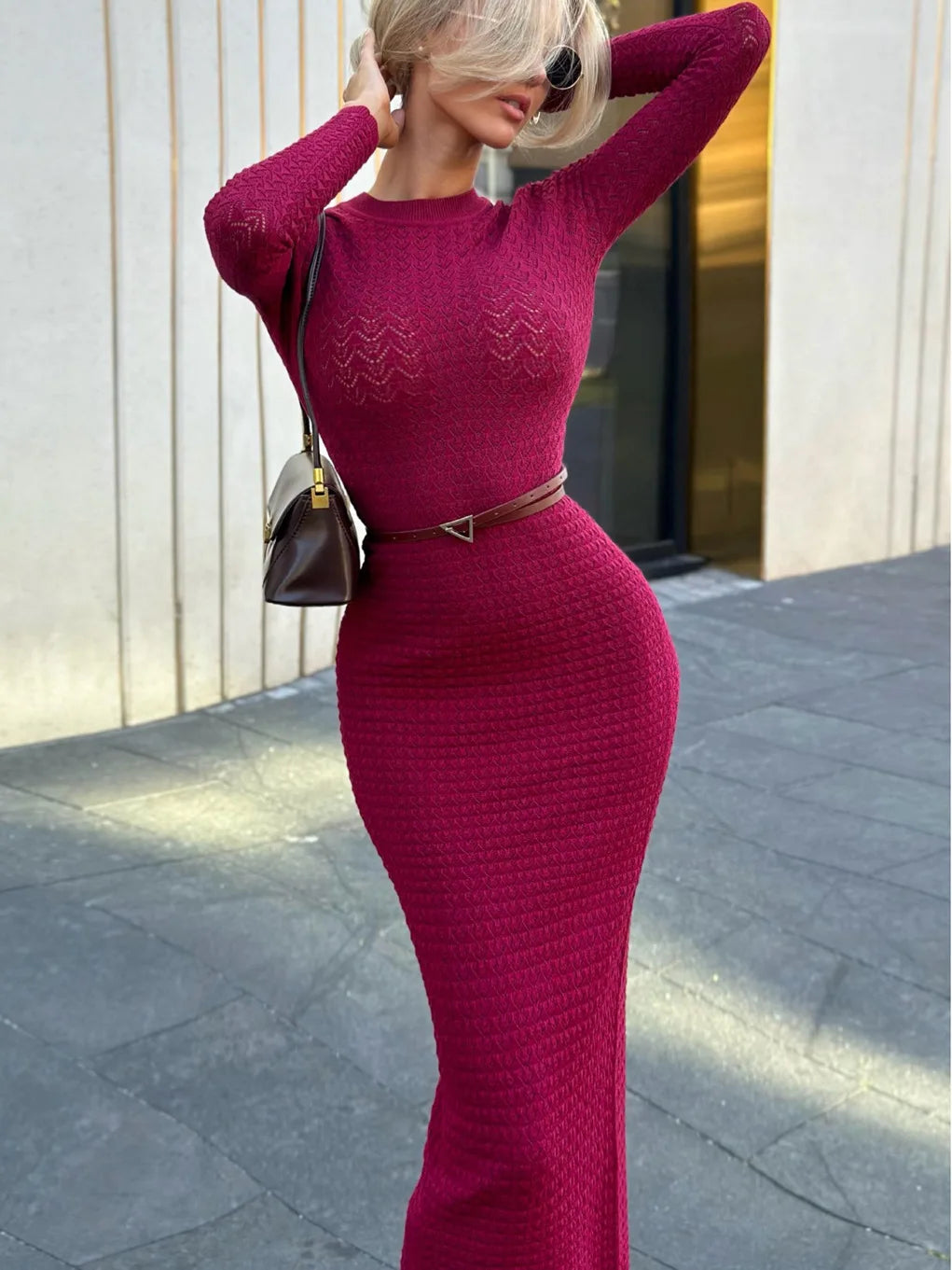 Woman wearing a burgundy dress with a belt, standing outdoors.
