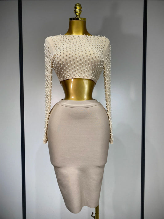Mannequin wearing a beige dress with pearl embellishments on a plain background
