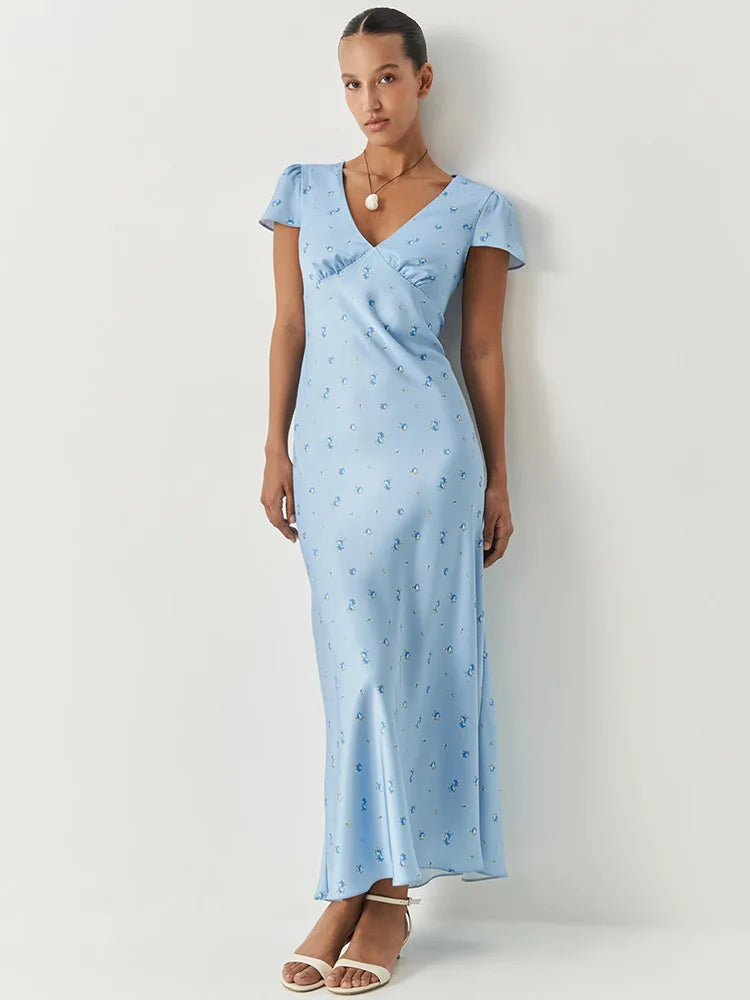 Woman wearing a light blue dress with a subtle pattern against a white background