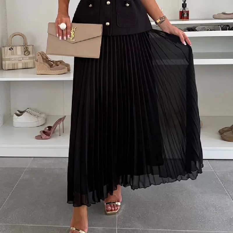Person wearing a black pleated skirt holding a beige handbag in a store setting.