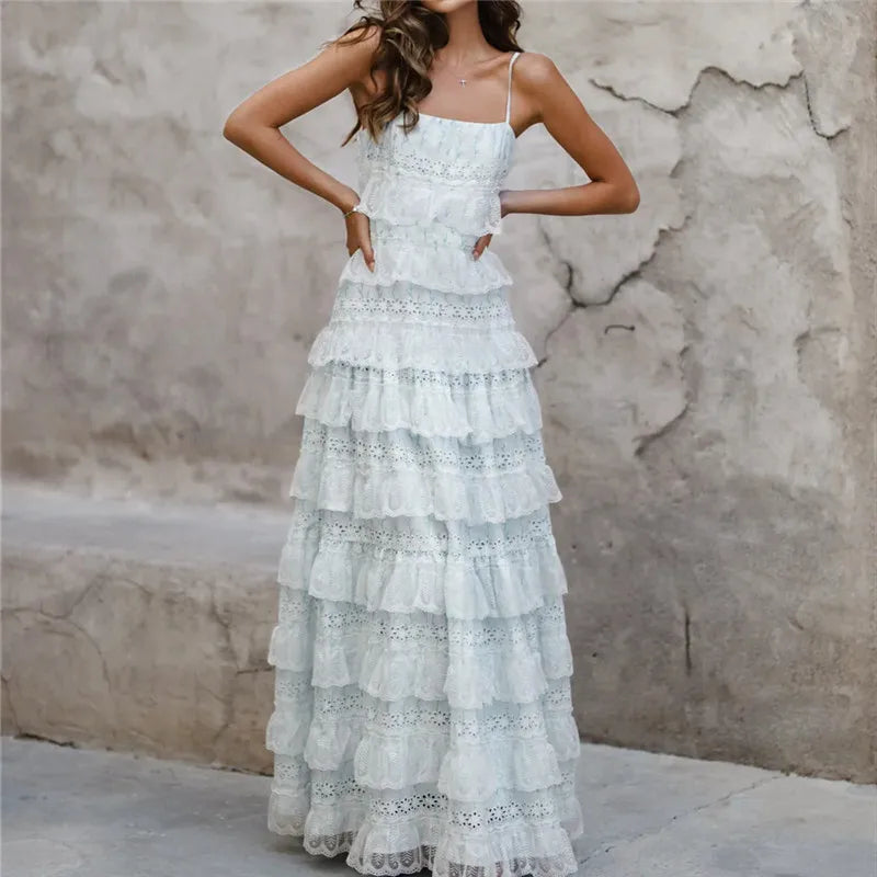 Woman wearing a white lace dress against a textured wall.