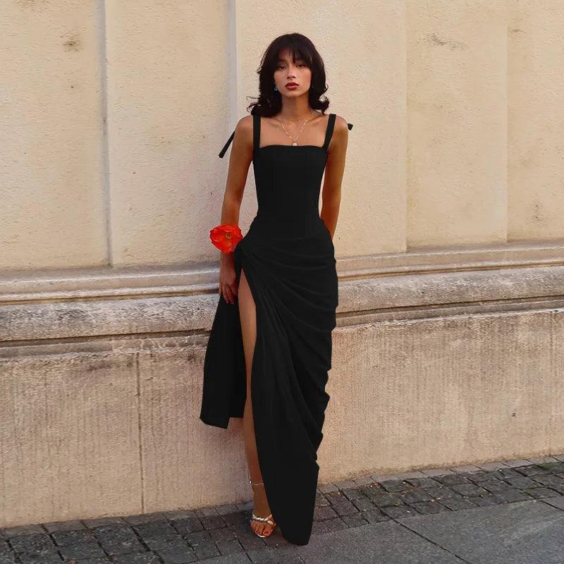 Woman in a black dress standing against a beige wall.
