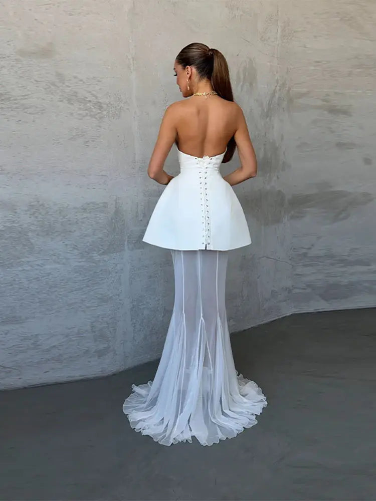 Woman wearing a white strapless dress with a textured wall background