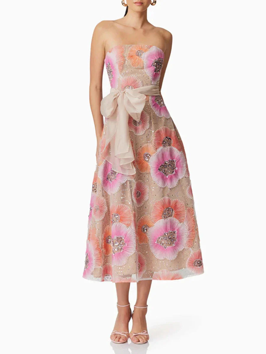 Woman wearing a floral strapless dress with a bow on a white background