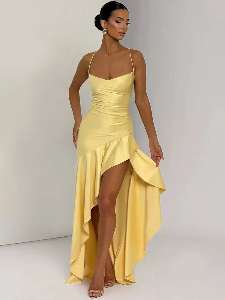 Woman wearing a yellow evening gown with a high-low hem on a plain background