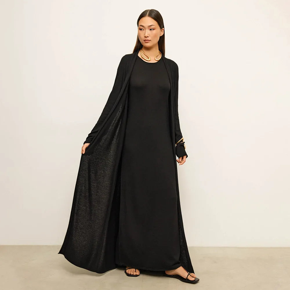 Woman wearing a black long-sleeve dress against a plain background