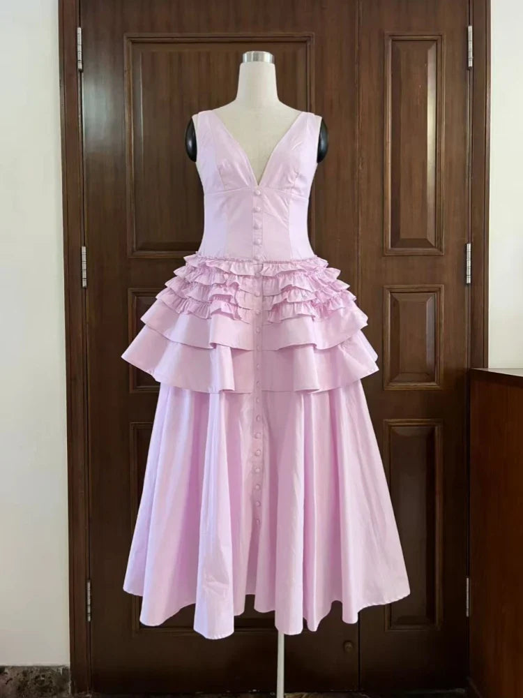 Pink ruffled dress on a mannequin against a wooden door.