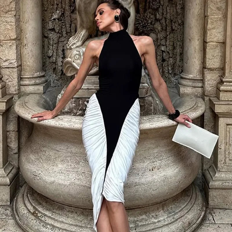 Woman in a black and white dress sitting on a stone fountain.