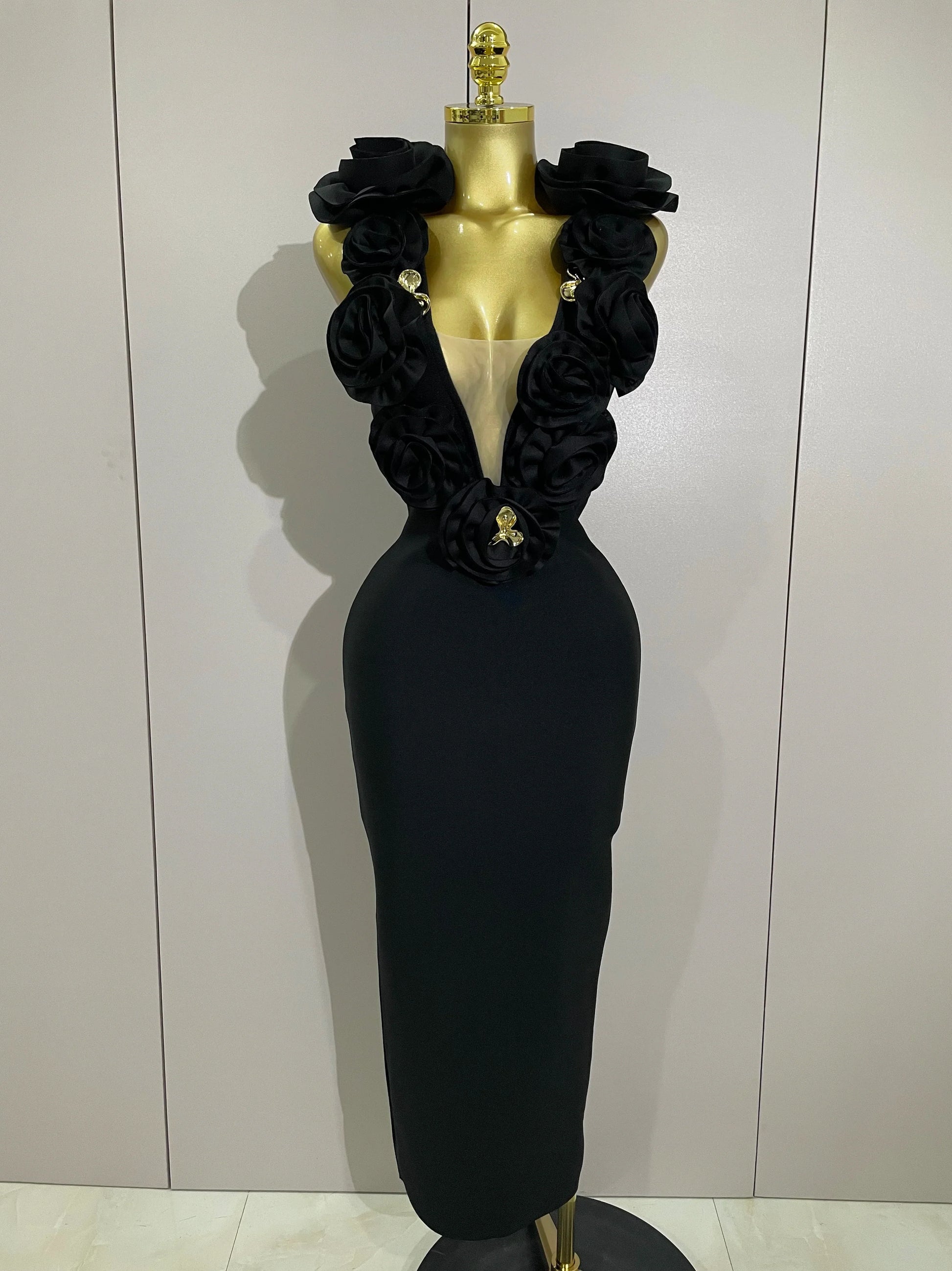 Black evening gown with floral details on a mannequin against a plain background