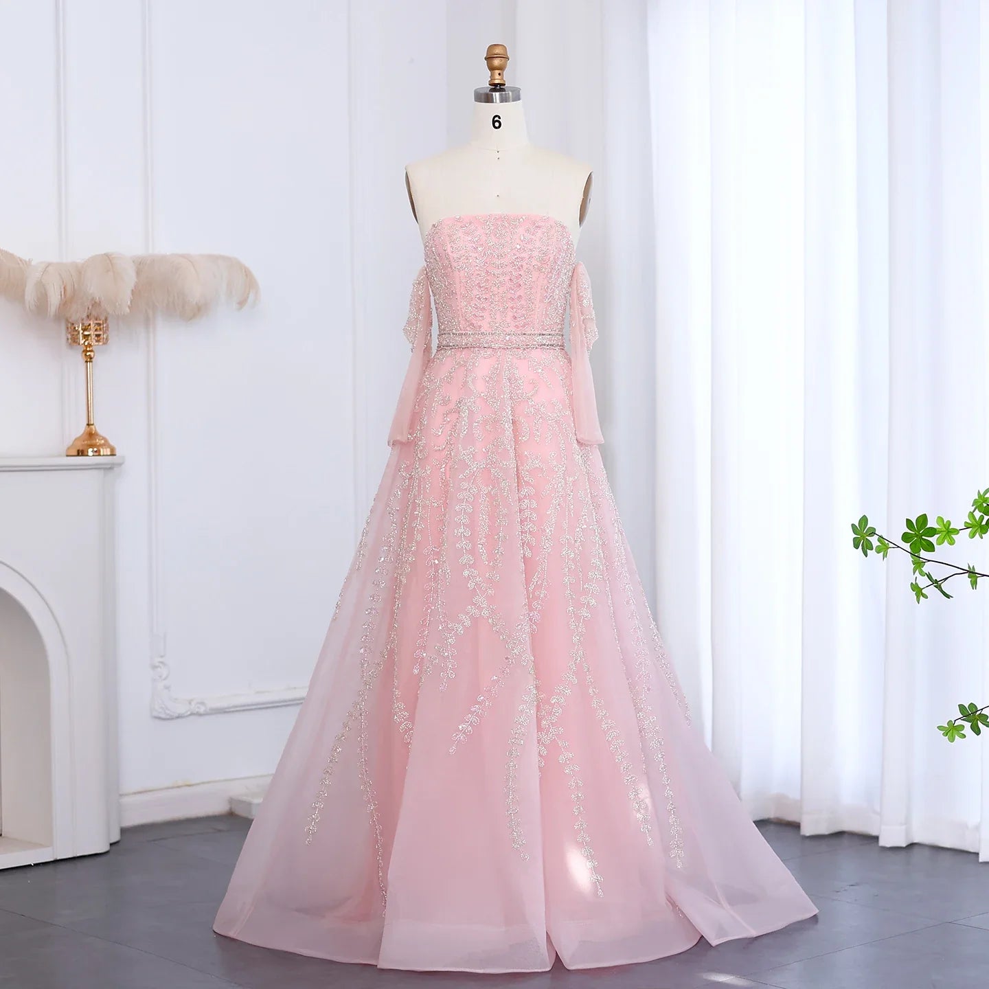 Pink evening gown on a mannequin against a white curtain background