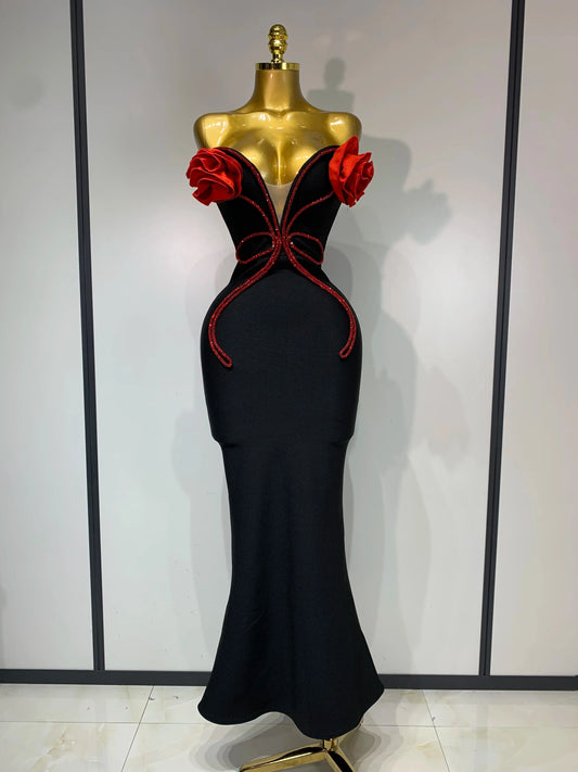 Black evening gown with red detailing on a mannequin against a plain background