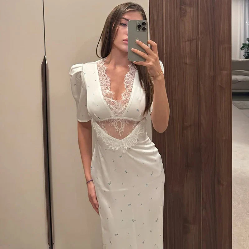 Woman taking a mirror selfie wearing a white lace dress.