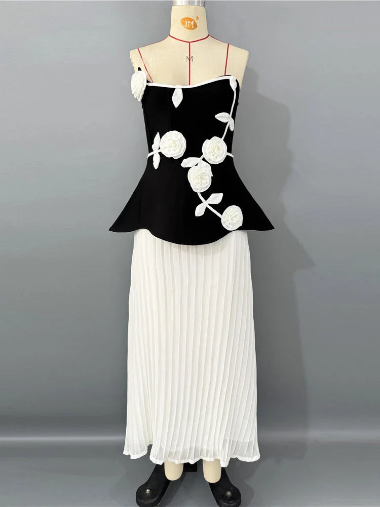 Black top with white floral patterns and a white pleated skirt on a mannequin against a gray background