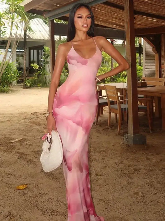 Woman in a pink dress standing outdoors with a wooden structure and plants in the background