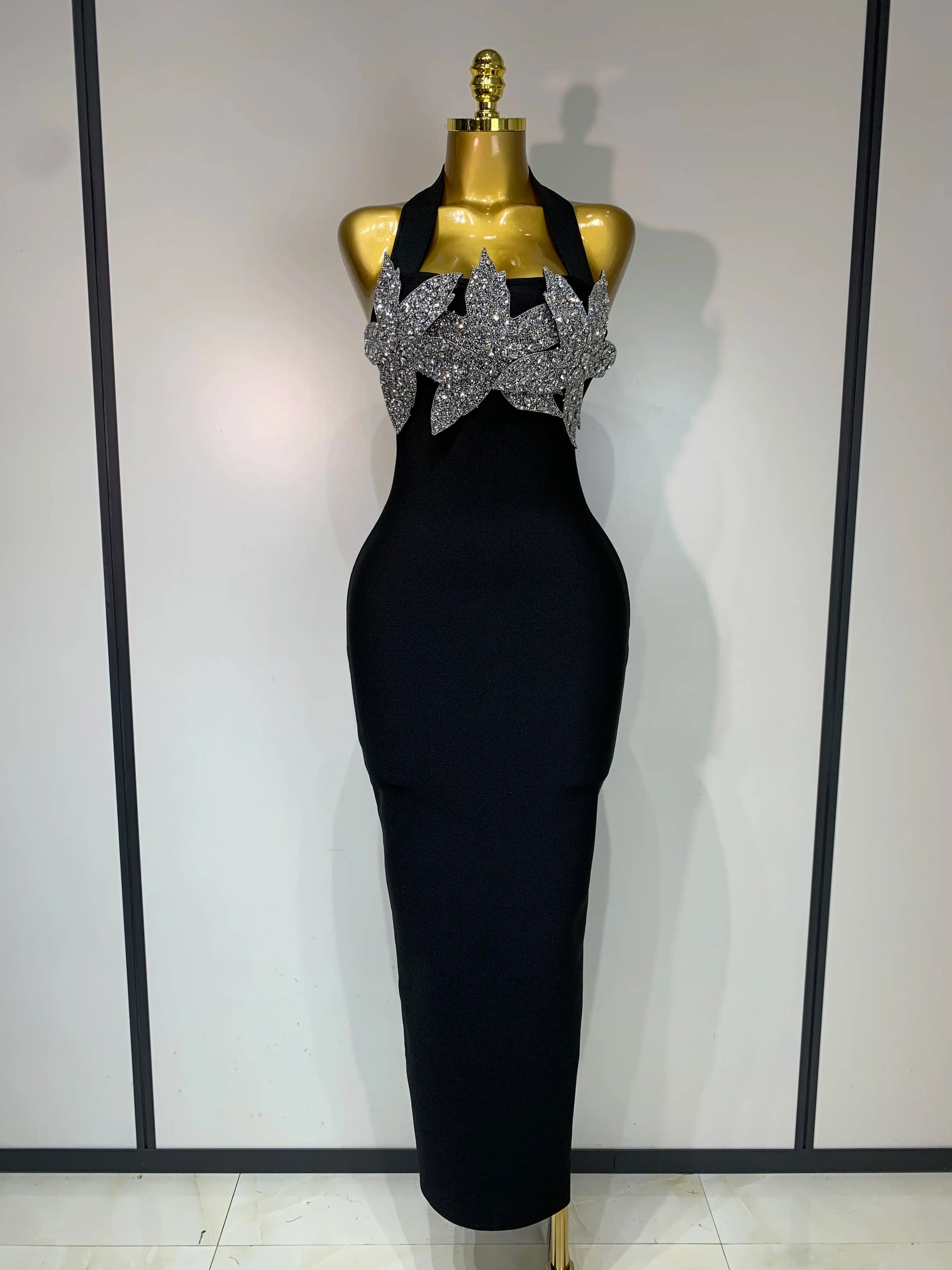 Black evening gown with silver embellishments on a mannequin against a white background