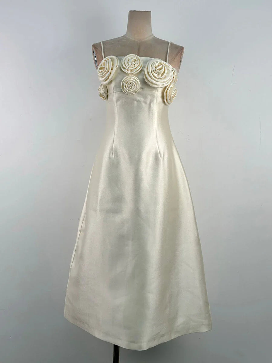 White dress with floral embellishments on a mannequin against a gray background