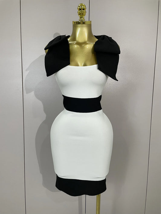 White dress with black accents on a mannequin against a plain background
