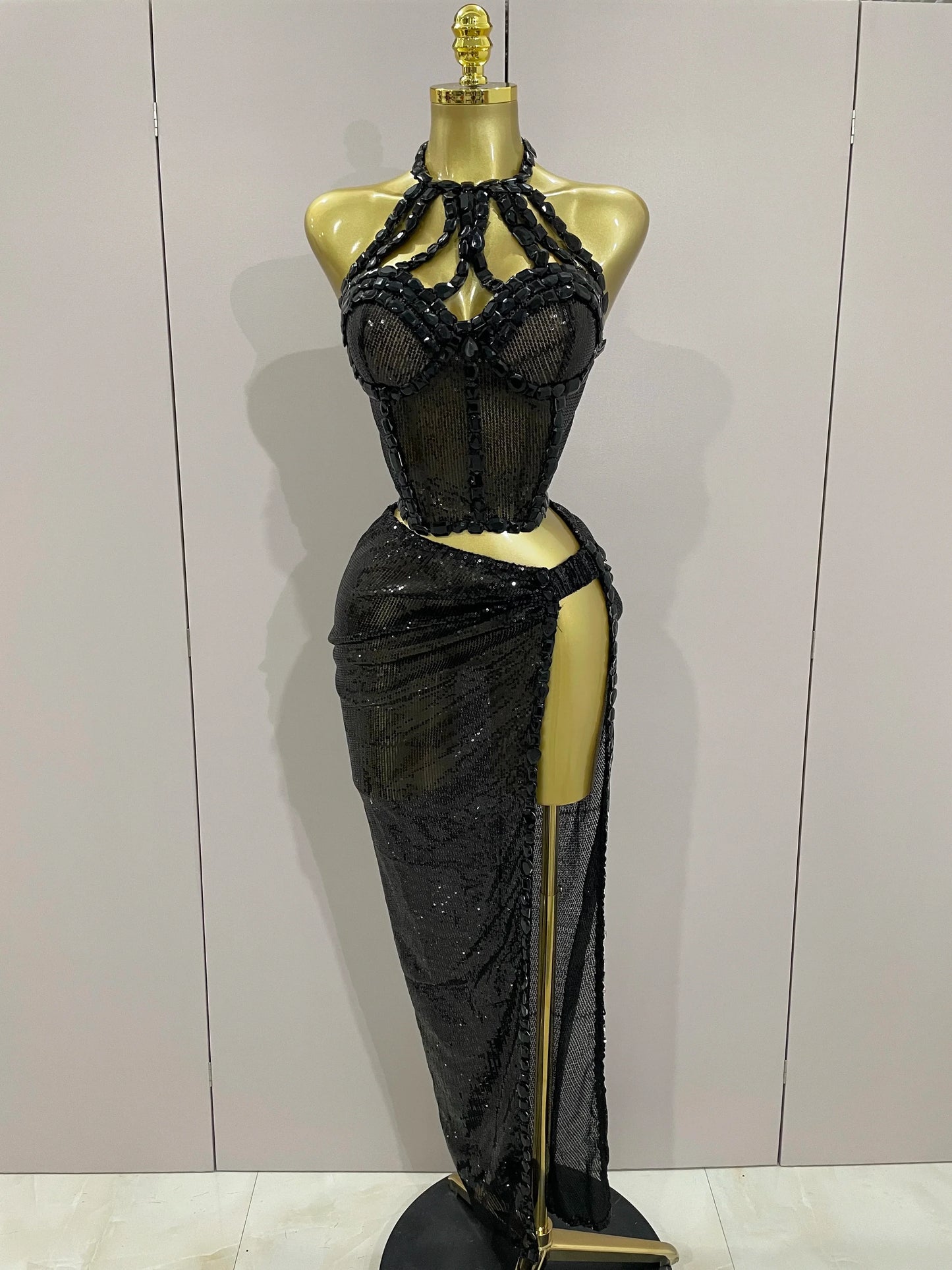 Black beaded evening gown on a mannequin against a plain background